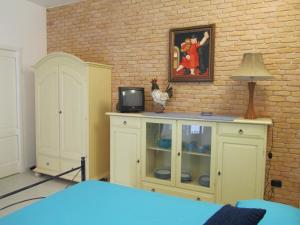 a room with a tv on a cabinet and a brick wall at Dorotea Studio in Lipari