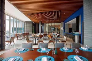 un restaurante con mesas, sillas y ventanas en DoubleTree by Hilton Melaka en Melaka