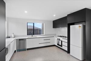eine Küche mit weißen Schränken und einem weißen Kühlschrank in der Unterkunft New house walk to Rototuna shopping Centre in Hamilton