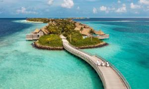 un grupo de personas caminando sobre un puente sobre el océano en Waldorf Astoria Maldives Ithaafushi en South Male Atoll