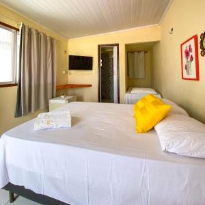 a bedroom with a large white bed with yellow pillows at Encanto do Sol Hospedagem in Icaraí