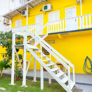 a yellow house with a white staircase in front of it at Encanto do Sol Hospedagem in Icaraí +17 photos