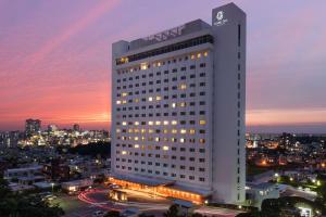 那霸DoubleTree by Hilton Naha Shuri Castle的一座白色的大建筑,以城市为背景
