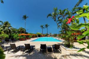 a resort with a pool and chairs and palm trees at DoubleTree by Hilton Hotel Naha Shuri Castle in Naha