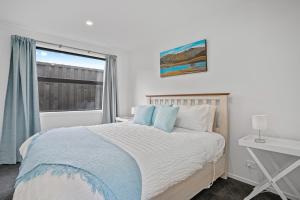 a white bedroom with a bed and a window at Duvauchelle Daydreamer - Duvauchelle Holiday Home in Duvauchelle