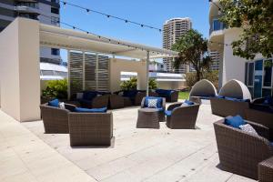 eine Terrasse mit Korbstühlen und blauen Kissen in der Unterkunft Hilton Surfers Paradise Hotel & Residences in Gold Coast