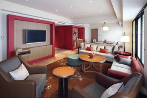 فندق هيلتون أوساكا  في أوساكا: غرفة معيشة مع كنب وتلفزيون بشاشة مسطحة