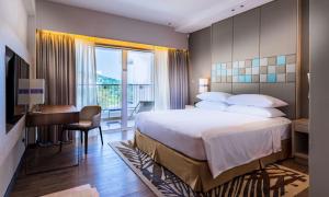 a bedroom with a bed and a desk and a window at DoubleTree Resort by Hilton Hotel Penang in Batu Ferringhi