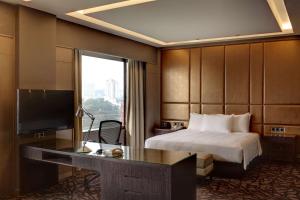 Habitación de hotel con cama y escritorio con TV. en Hilton Petaling Jaya en Petaling Jaya