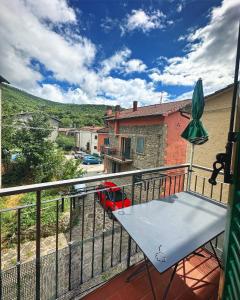 einen Balkon mit einem Tisch und einem roten Auto auf einer Straße in der Unterkunft Casa Renata in Arcidosso