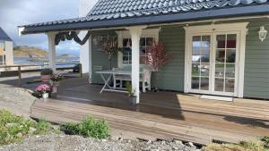 una casa con una terraza de madera con una mesa. en Pittelille - supercozy small luxury in Henningsvær en Henningsvær