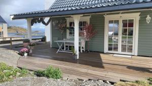 a house with a wooden deck with a table on it at Pittelille - supercozy small luxury in Henningsvær in Henningsvær