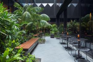 シドニーにあるウェスト ホテル シドニー キュリオ コレクション バイ ヒルトンのテーブルと椅子、植物のあるレストラン