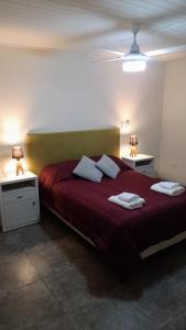1 dormitorio con 1 cama grande de color rojo y 2 mesitas de noche en Casa vacacional COSTA CALMA en Carhué
