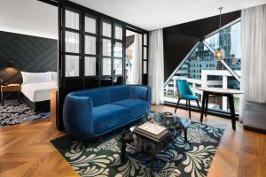 un salon avec une chaise bleue et un canapé bleu dans l'établissement West Hotel Sydney, Curio Collection by Hilton, à Sydney