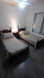 2 camas en una habitación con ventana en Casa vacacional COSTA CALMA en Carhué