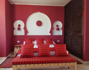 a bedroom with red walls and a bed with red pillows at Dar Amphora Menzel in Midoun