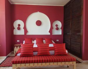a bedroom with red walls and a bed with red pillows at Dar Amphora Menzel in Midoun +46 photos