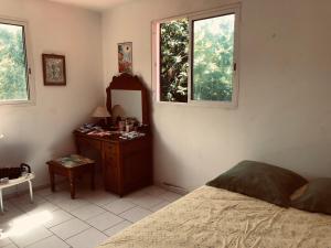 1 dormitorio con 1 cama, vestidor y 2 ventanas en Ti Vanillier, en Petit-Bourg