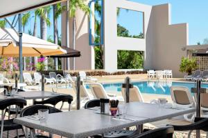 a restaurant with tables and chairs next to a swimming pool at DoubleTree by Hilton Esplanade Darwin in Darwin
