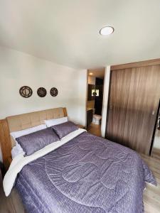a bedroom with a large bed with a purple comforter at Sabaneta Apto tres habitaciones a 10 minutos CC Mayorca in Sabaneta