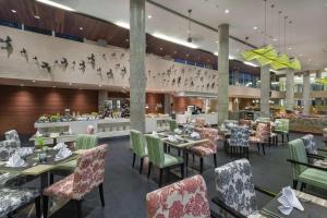 une salle à manger avec des tables et des chaises dans un restaurant dans l'établissement Hilton Garden Inn Bali Ngurah Rai Airport, à Kuta