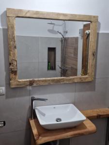 een badkamer met een witte wastafel en een spiegel bij Bujtinat Skenderi Gjinar in Gjinar