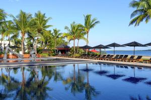 basen z leżakami i parasolami na plaży w obiekcie Hilton Fiji Beach Resort and Spa w mieście Denarau
