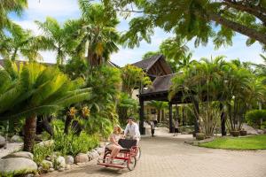 a man and woman riding a red wagon in a resort at DoubleTree by Hilton Fiji - Sonaisali Island in Nadi