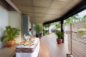 uma mulher de pé num convés com uma mesa com comida em DoubleTree by Hilton Fiji - Sonaisali Island em Nadi