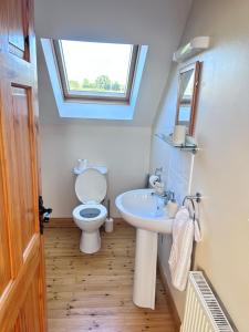a bathroom with a toilet and a sink and a window at 46 Dunalinn in Culdaff
