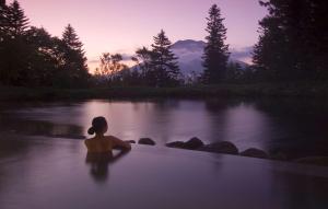 Eine Frau, die in einer Badewanne im Fluss sitzt. in der Unterkunft Hilton Niseko Village in Niseko