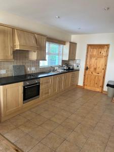 a large kitchen with wooden cabinets and a door at Dunalinn, Culdaff in Culdaff +9 photos