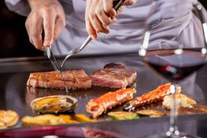 a person cooking meat and vegetables on a grill at Hilton Niseko Village in Niseko