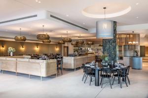 Doubletree By Hilton Karaka في أوكلاند: مطعم بطاولات وكراسي وبار