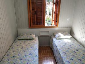 two beds sitting in a room with a window at Gramado Família in Gramado