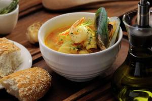 a bowl of soup on a wooden table with bread at DoubleTree by Hilton Gurgaon New Delhi NCR in Gurgaon