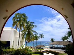 een uitzicht op de oceaan vanuit een gebouw met palmbomen bij Villa DALIJÚ in Santa María Huatulco