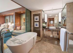 a bathroom with a tub and a bedroom at Conrad Bangkok in Bangkok