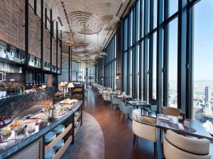 a restaurant with long tables and chairs and windows at Conrad Osaka in Osaka