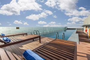 a swimming pool with benches on the deck of a building at DoubleTree by Hilton Ahmedabad in Ahmedabad