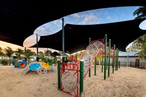 une aire de jeux dans le sable avec un auvent noir dans l'établissement Solitary Islands Resort, à Wooli