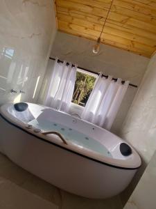 a large white bath tub in a bathroom with a window at Chalés Canto da Serra in Monte Verde +34 photos