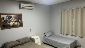ブラジリアにあるLinda casa em condomínio fechadoのベッドルーム1室(ベッド1台、椅子、絵画付)