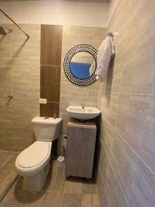 ein Badezimmer mit einem WC, einem Waschbecken und einem Spiegel in der Unterkunft IW-Apto en la vega, cerca al CC Viva in Villavicencio