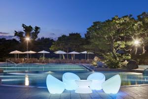 a pool at night with white chairs and umbrellas at Hilton Gyeongju in Gyeongju