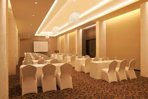 a conference room with white tables and chairs and a screen at DoubleTree by Hilton-Pune Chinchwad in Pune