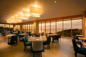 a restaurant with tables and chairs and large windows at Hilton Club The Beach Resort Sesoko in Motobu
