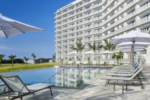 a hotel with chairs and a pool in front of a building at Hilton Club The Beach Resort Sesoko in Motobu