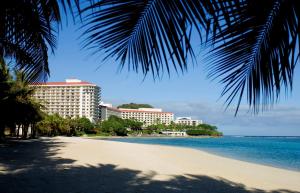 a beach with a palm tree and some buildings at Hilton Guam Resort & Spa in Tumon